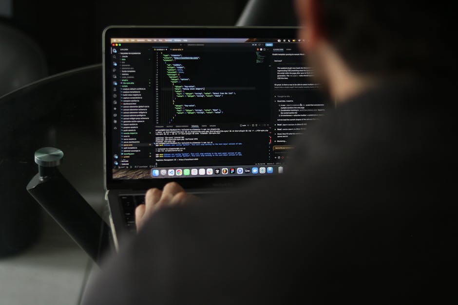 A person sitting in a vehicle using a laptop to perform garden maintenance planning, with the laptop screen displaying lines of code and a web-based interface. The individual is slightly out of focus,